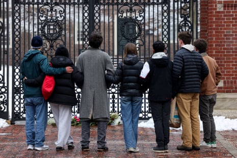 Students stand in front of the Van Wickle Gates after placing flowers following the shooting at Brown University.