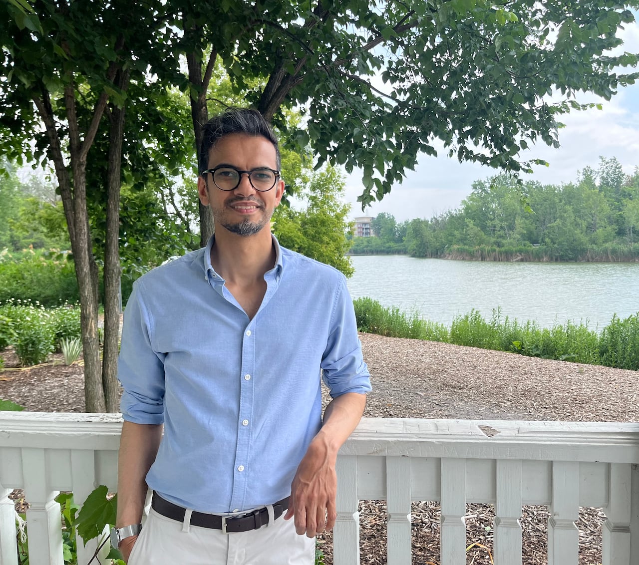 A man leans on a white porch.
