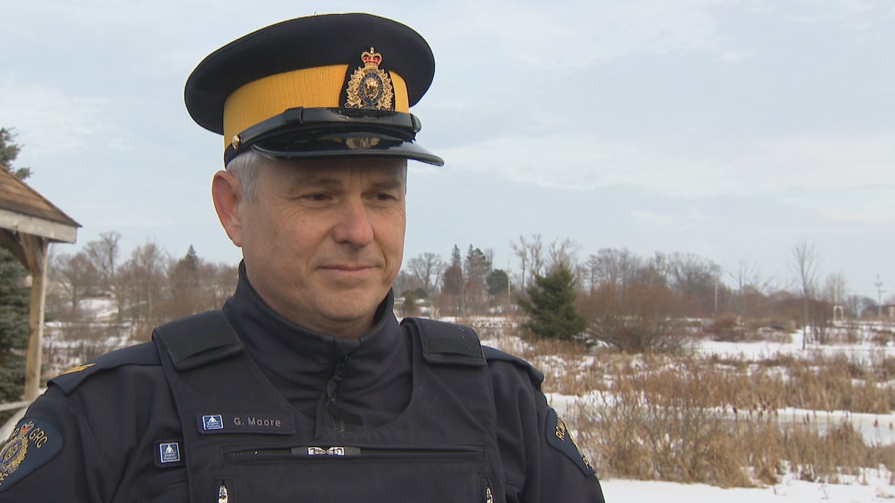 A police officer in a uniform and hat stands outside