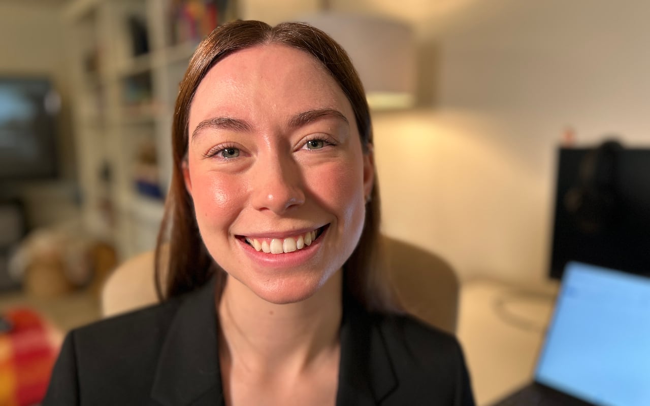 A woman smiles at camera in a black blazer.
