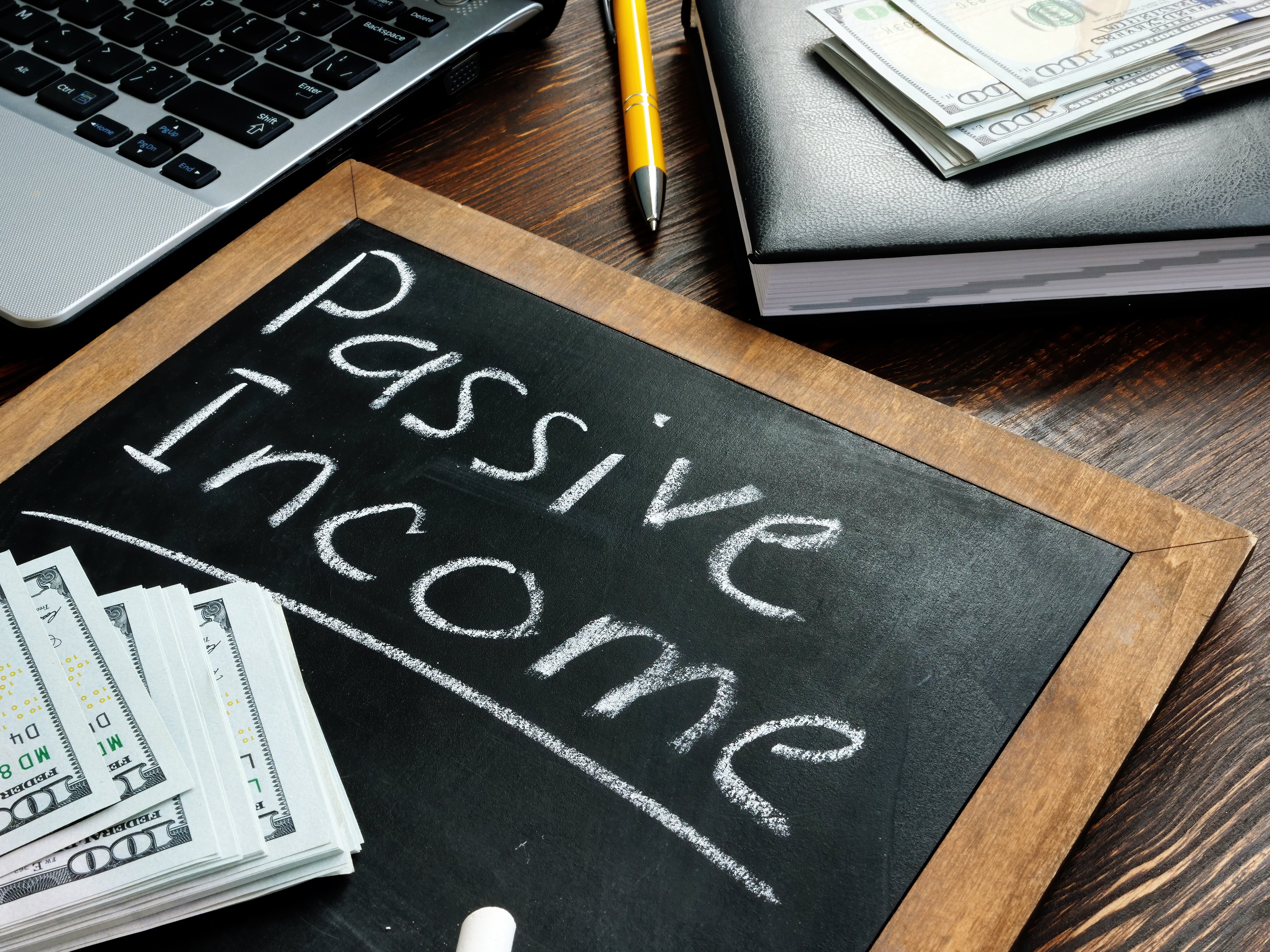 "Passive Income" written on a chalkboard with money sitting on top.