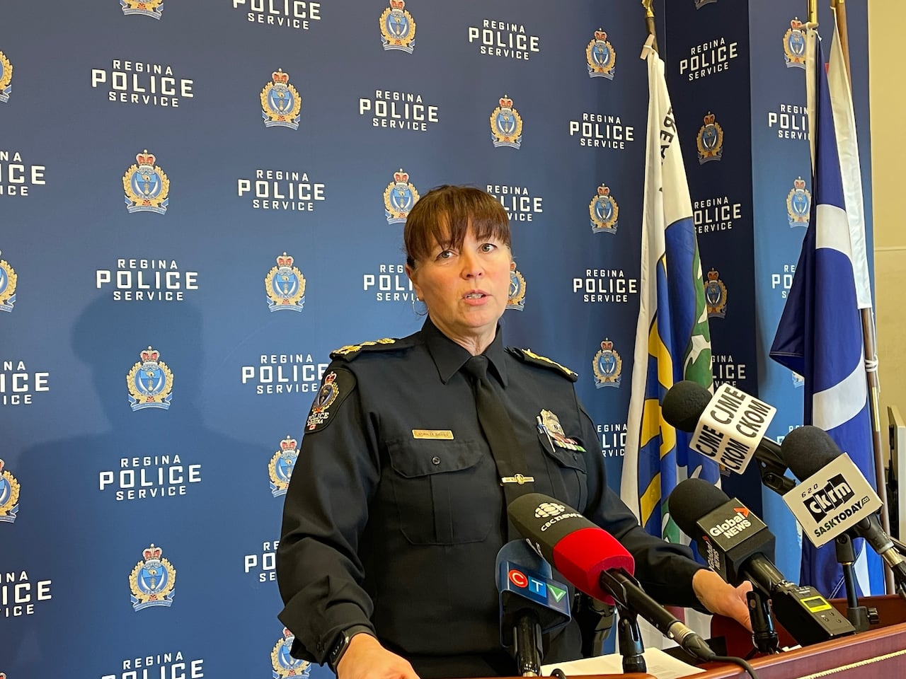 A woman in a black police uniform stands at a podium.