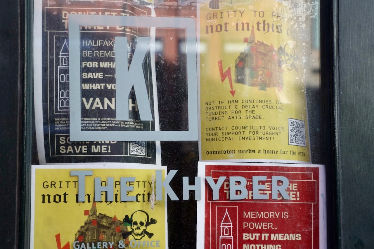 Colourful posters urging municipal investment for the Khbyer are seen behind glass of the front door