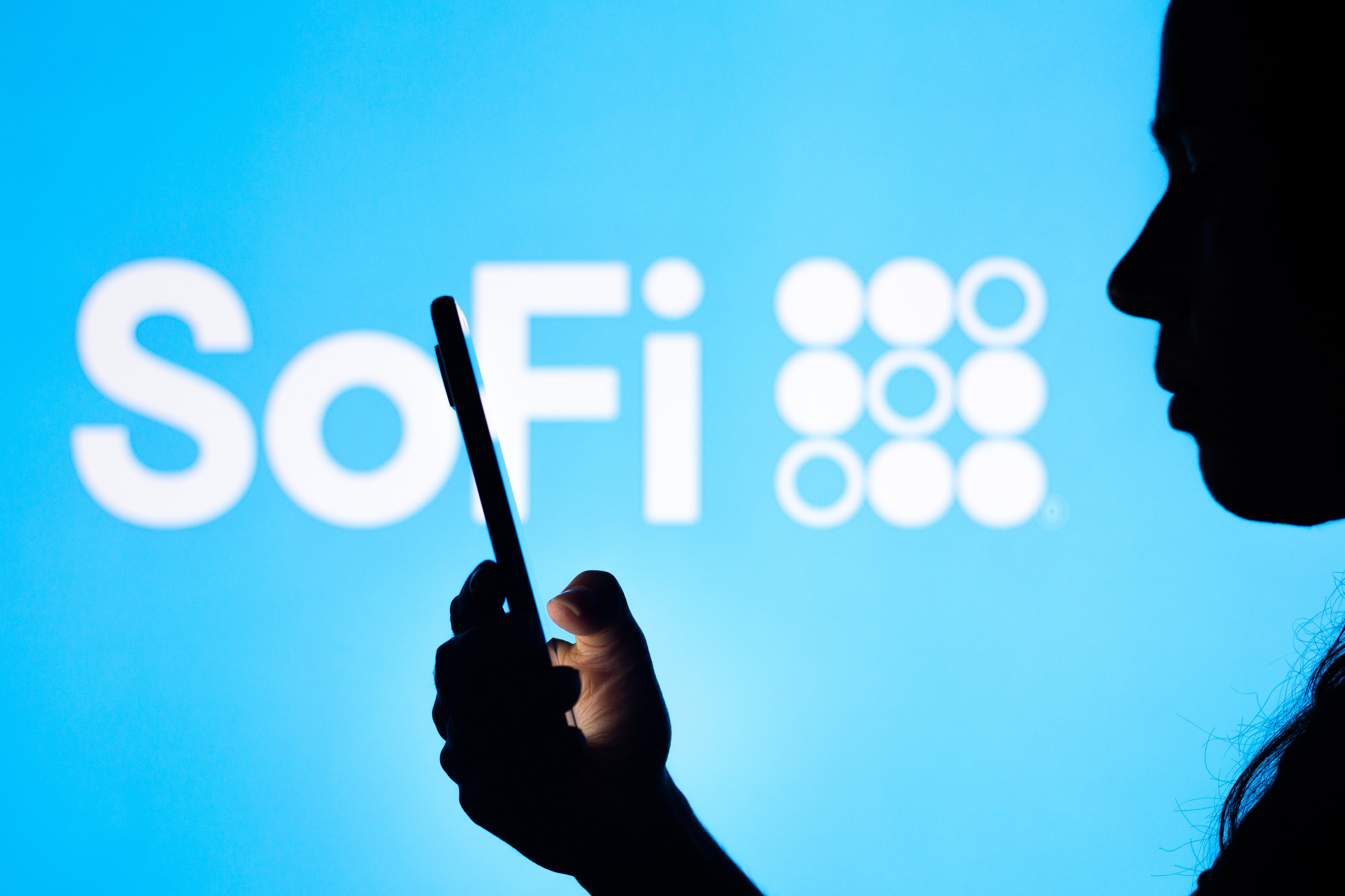 Person using smartphone with SoFi logo in the background.