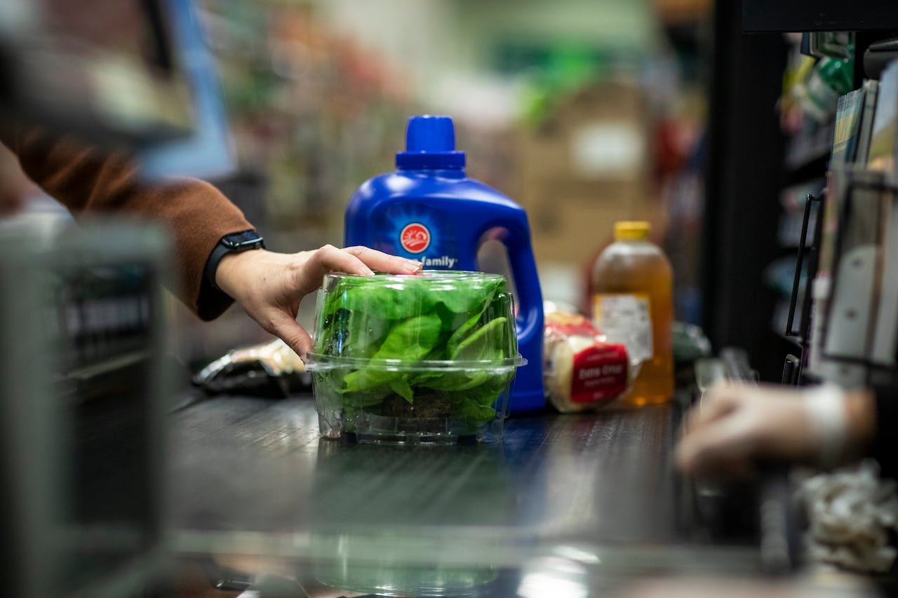 A container of lettuce on a grocery checkout belt