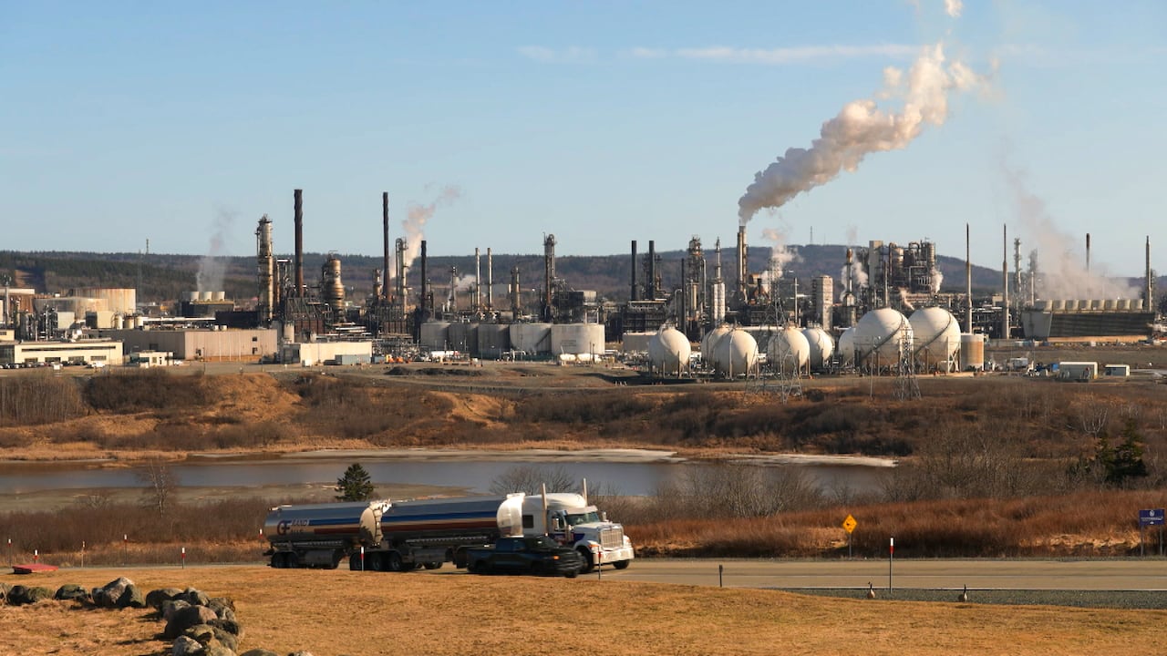 A refinery is shown with a truck in the foreground.