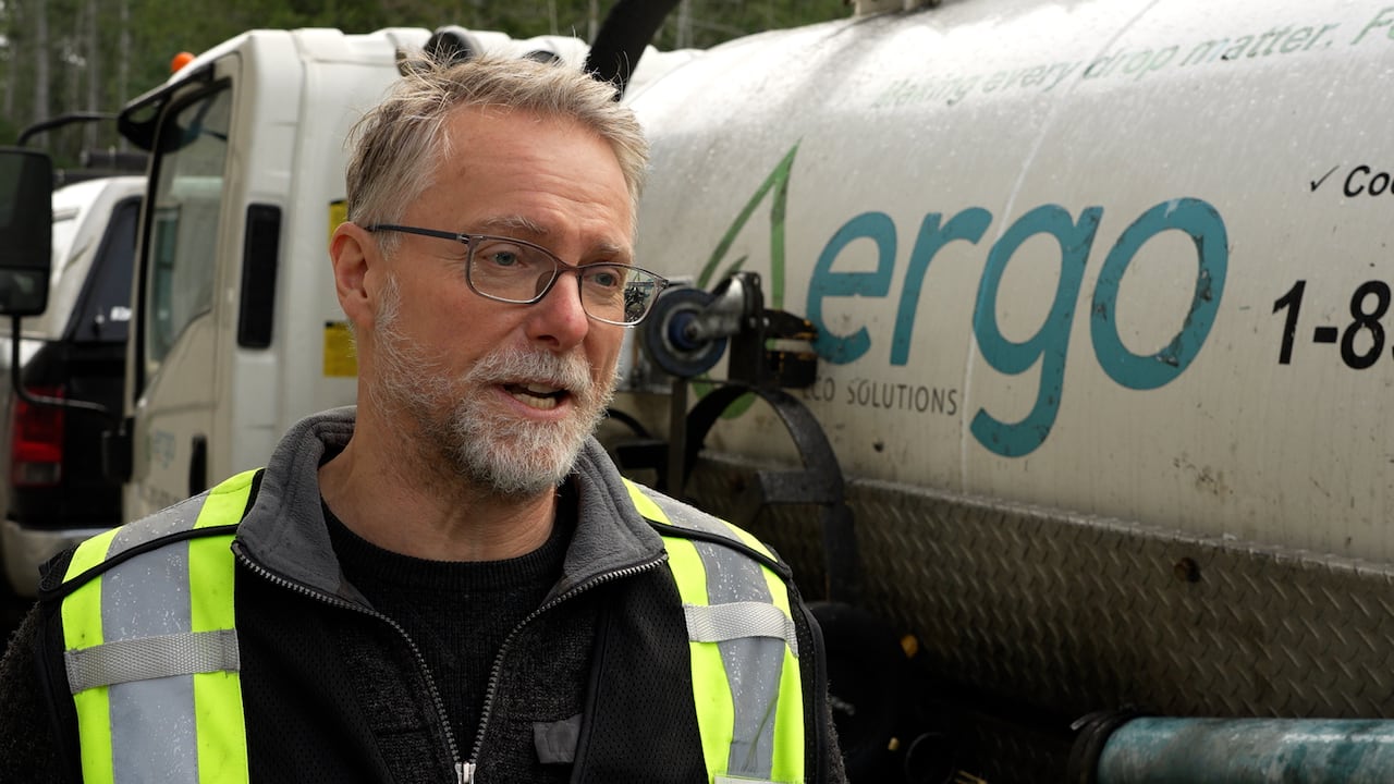 Brian Roberts stands in front of a large truck used to vacuum up used cooking oil from restaurants. 
