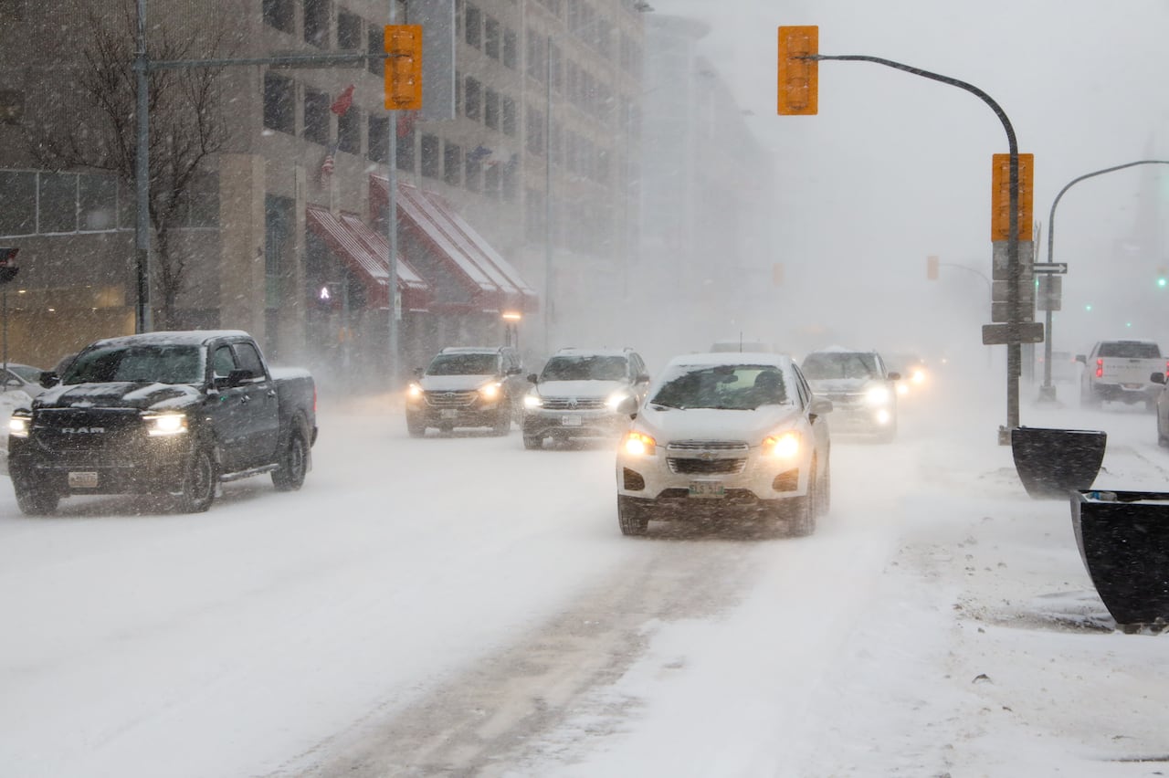 Cars on a snow covered road, with blowing snow