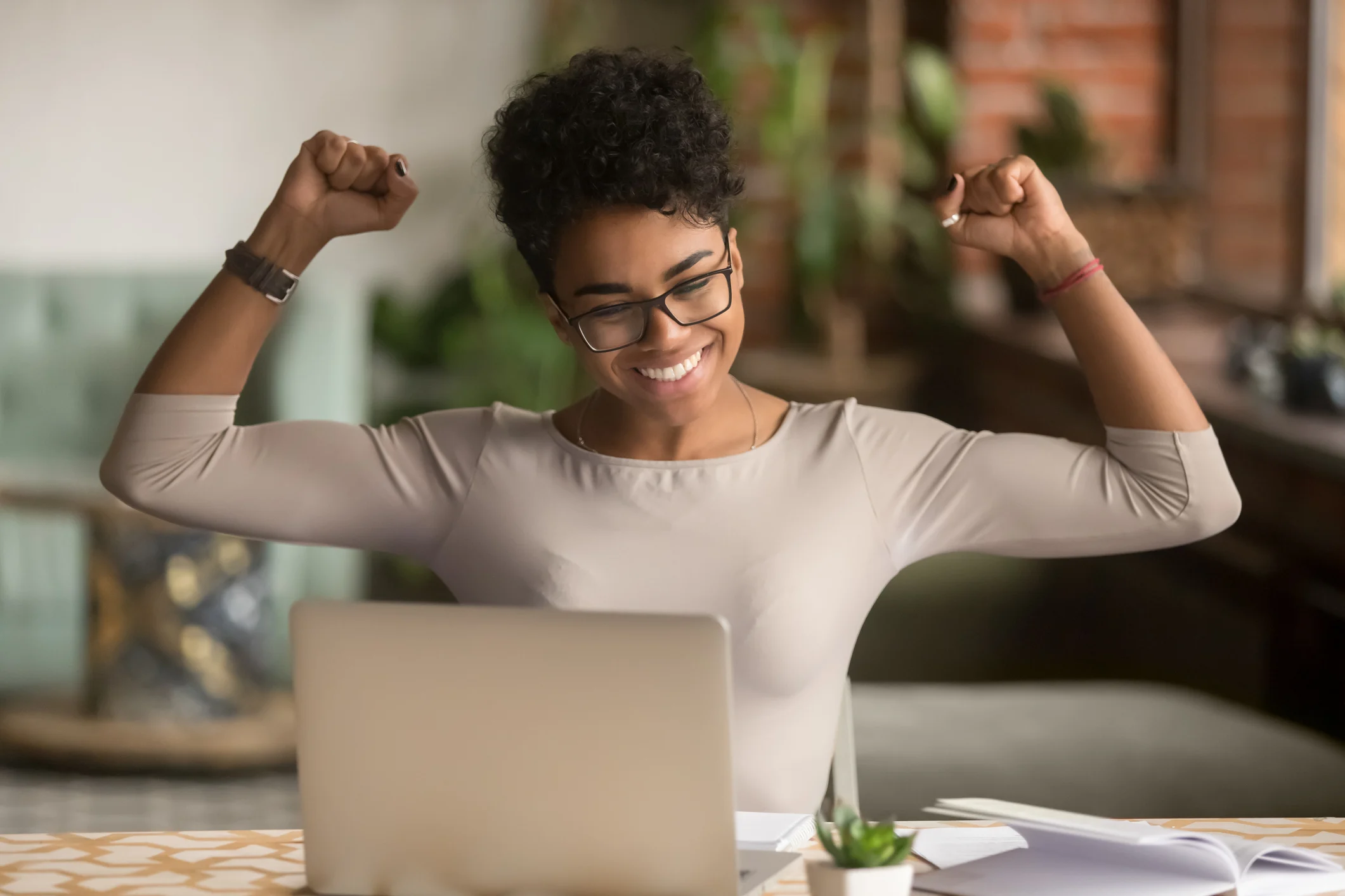A person sitting at a computer strikes a celebratory pose.