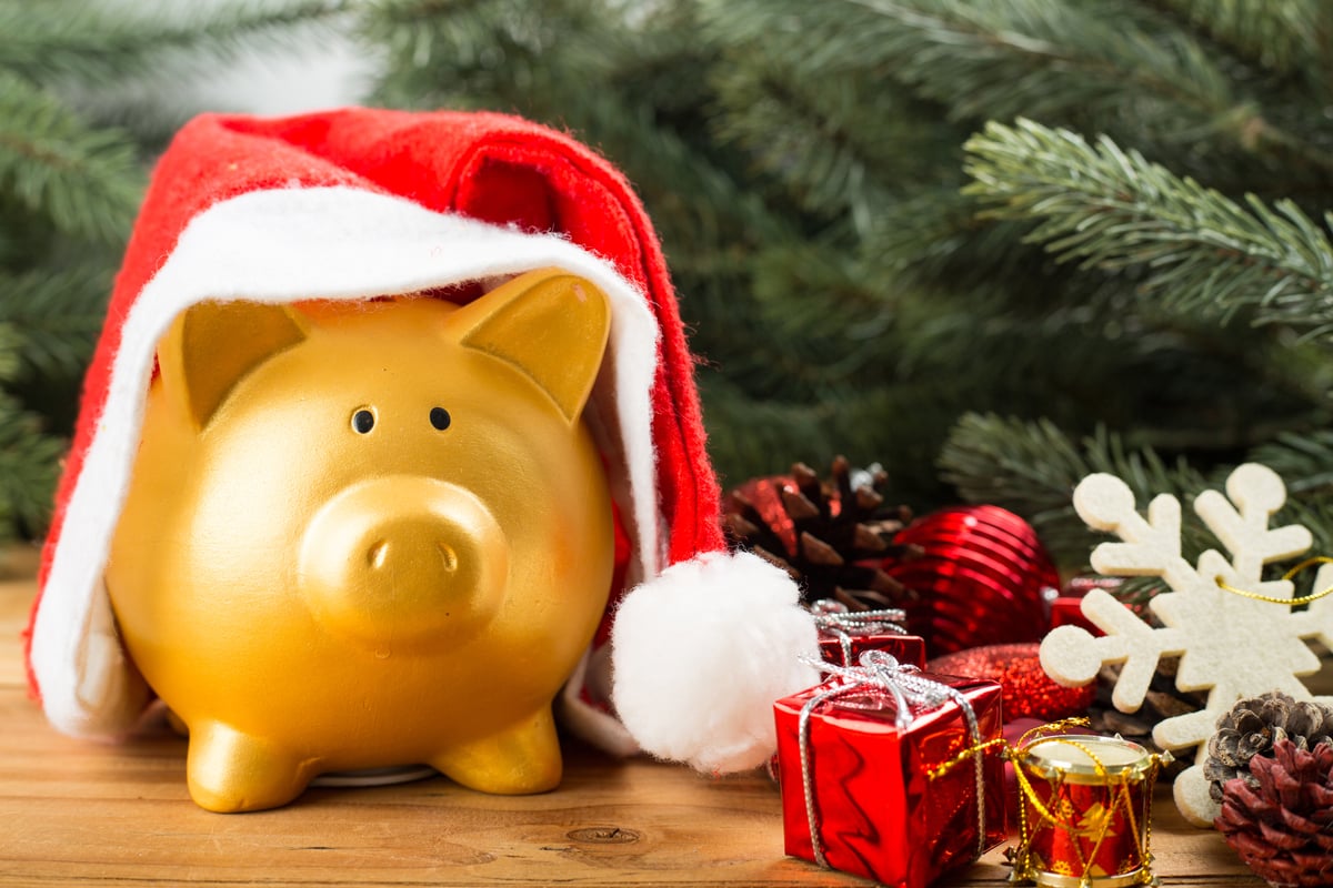 A gold piggy bank sitting under a Christmas tree.
