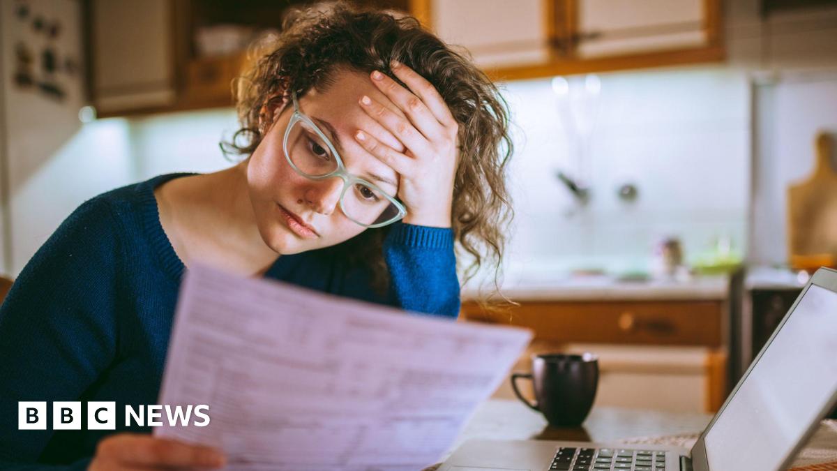 A woman looking at documents while holding her head in her hand