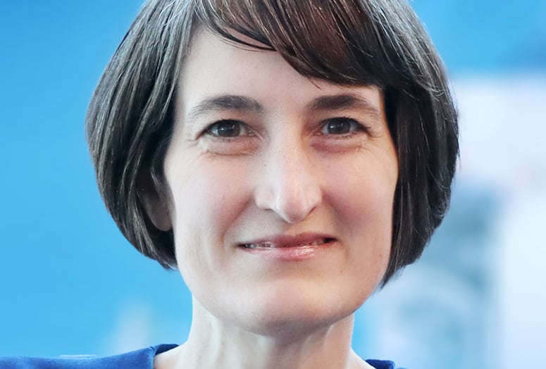 A portrait of a smiling woman in a blue top.