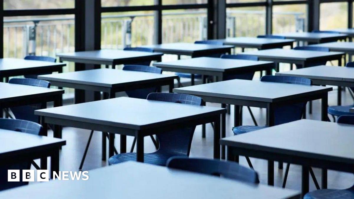 A set of empty chairs, sat at standalone desks in a brightly-lit room.