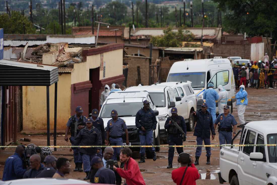 South African police gather at the scene of a mass shooting where gunmen killed nine and injured at least 10 in a pub in Bekkersdal, South Africa, Sunday, Dec. 21, 2025.