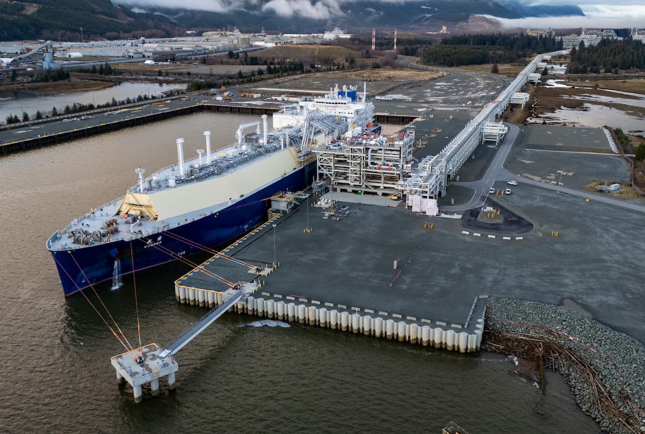 An aerial view of a shipping port with a large white and blue painted ship docked at it.