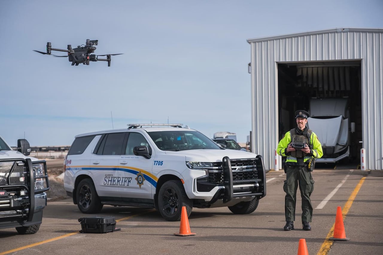 A law enforcement official uses a drone near a vehicle.