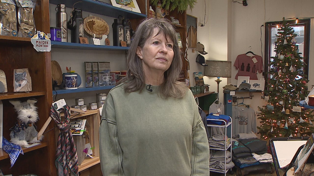 A woman stands in front of a gift shop.
