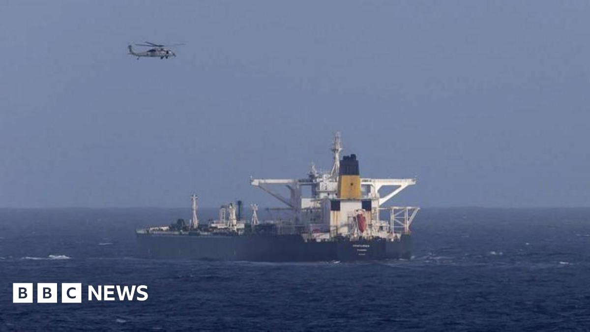 A helicopter flies over a ship in blue waters