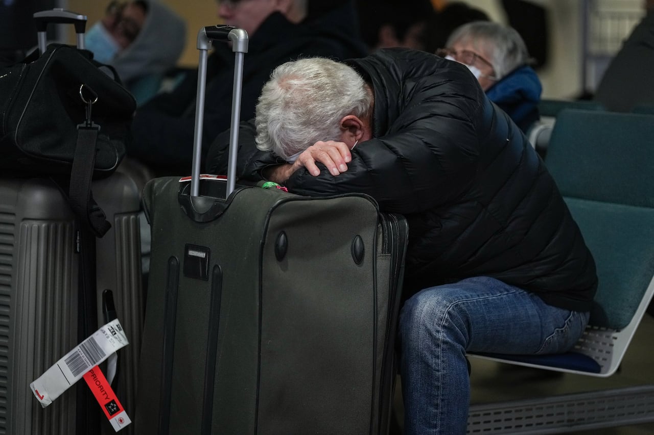 A photo of a man who is resting his head on his luggage.