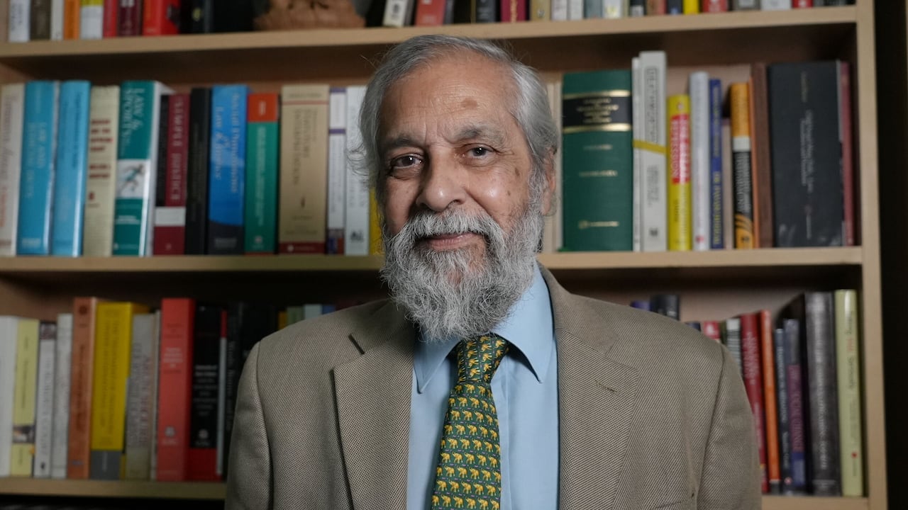 A person stands in front of several shelves filled with books.