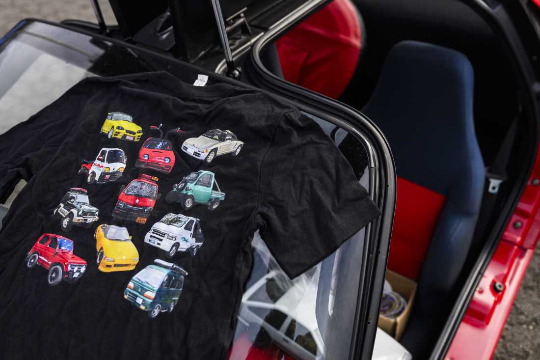 This photo shows a black T-shirt that features rows of kei cars, pickups and vans.