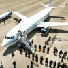 An aerial view of people boarding a plane as law enforcement officers watch in formation.