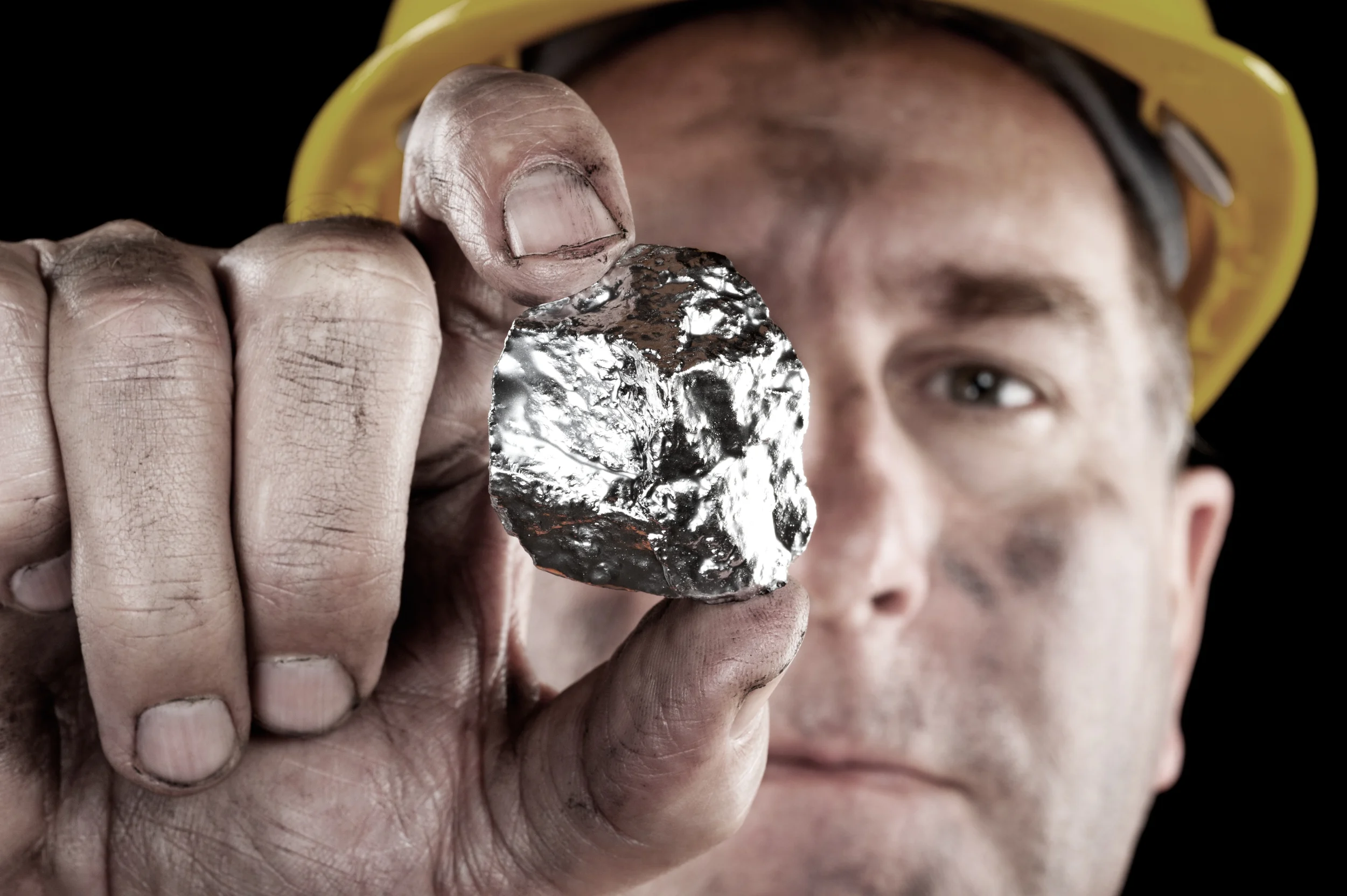 A miner is holding a piece of raw silver. 