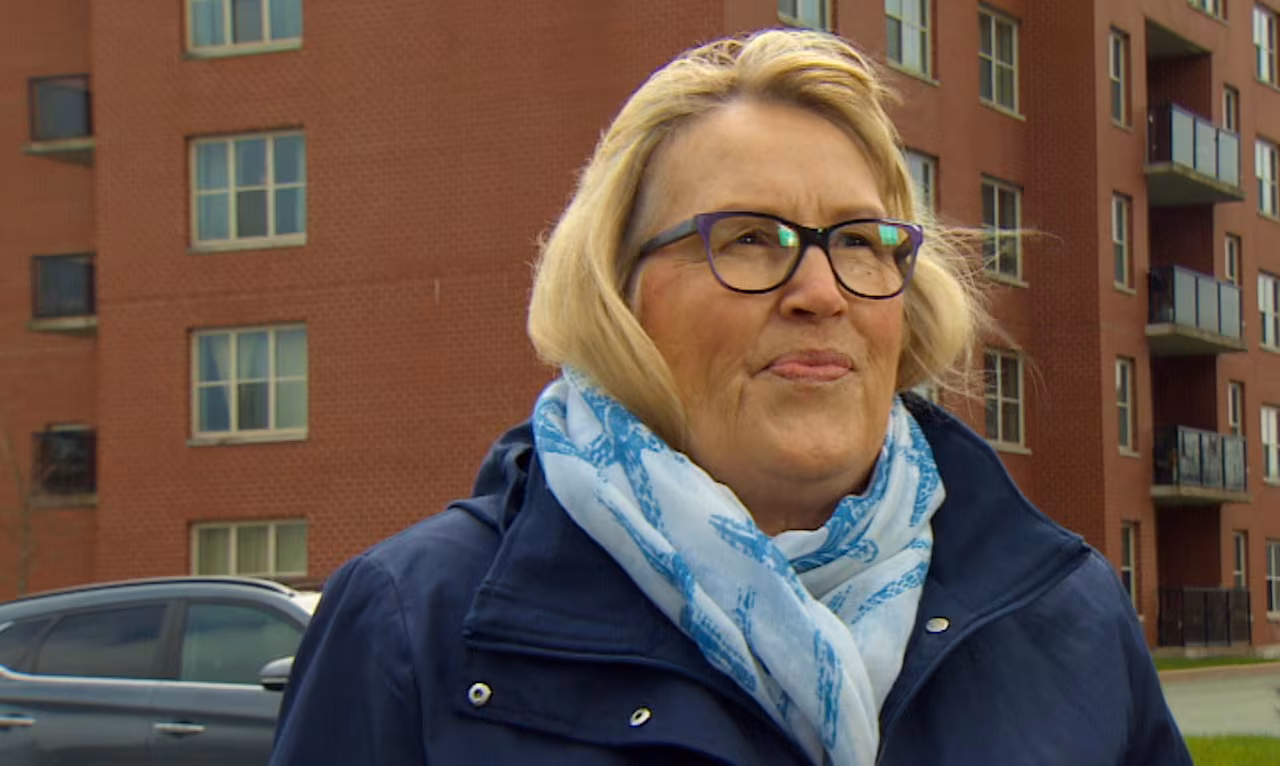 A woman in a blue jacket looks at the camera