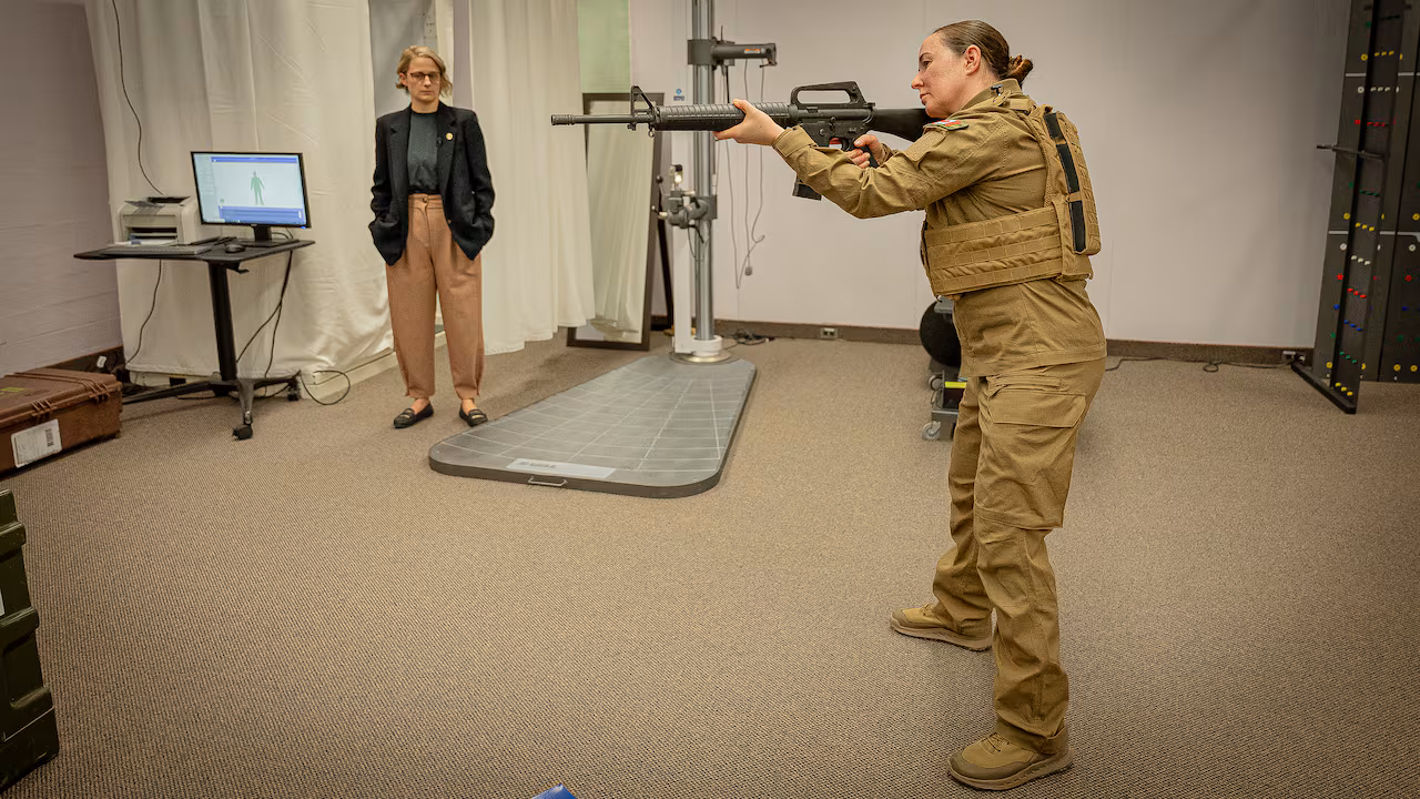 Emma Moon with the Department of National Defence watching Lt.-Col. Melanie Lake test out a prototype of the army's new uniform and body armour system in the works. She's shouldering a rifle.