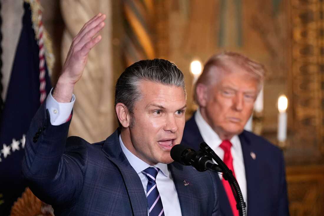 Defense Secretary Pete Hegseth speaks as President Donald Trump looks on, at Trump's Mar-a-Lago club, Monday, Dec. 22, 2025, in Palm Beach, Fla.