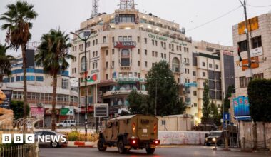 An Israeli military vehicle moves in a street outside the building in Ramallah, in the Israeli-occupied West Bank, where Al Jazeera's office was located before it was ordered to close (22 September 2024)