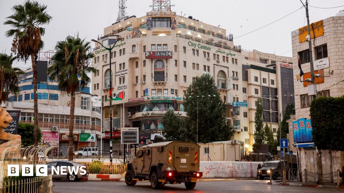 An Israeli military vehicle moves in a street outside the building in Ramallah, in the Israeli-occupied West Bank, where Al Jazeera's office was located before it was ordered to close (22 September 2024)