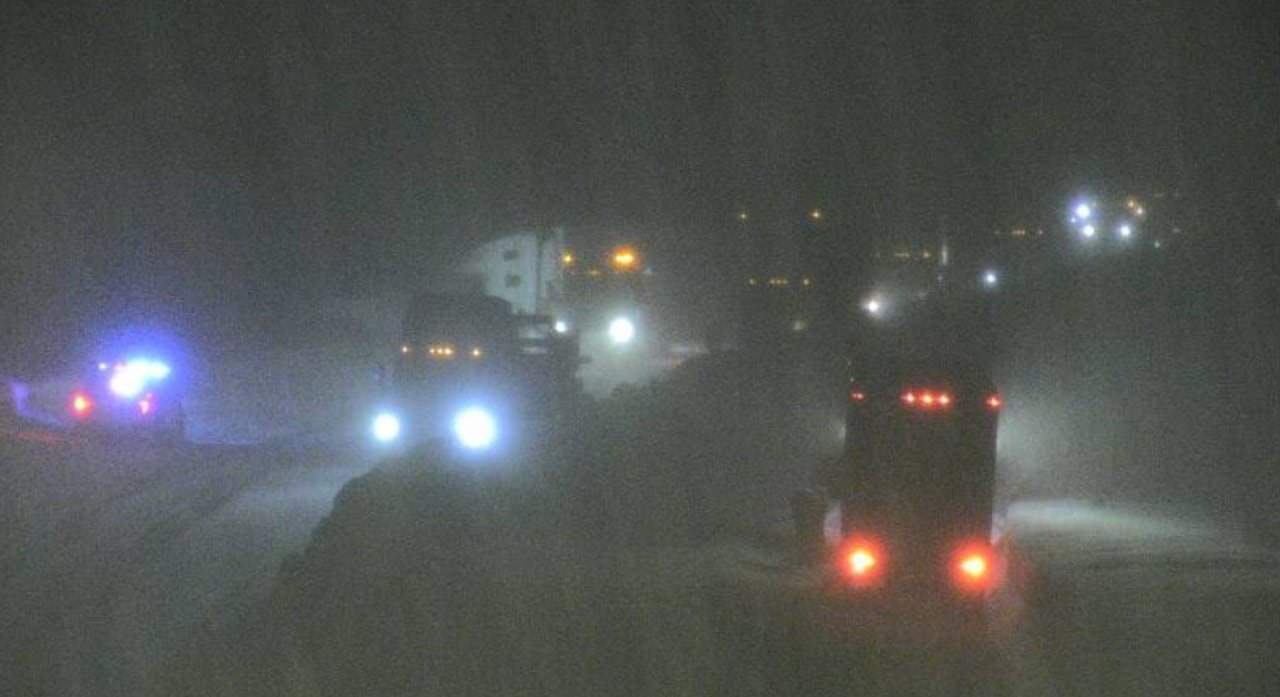 A dark photos hows multiple vehicles on a snowy highway
