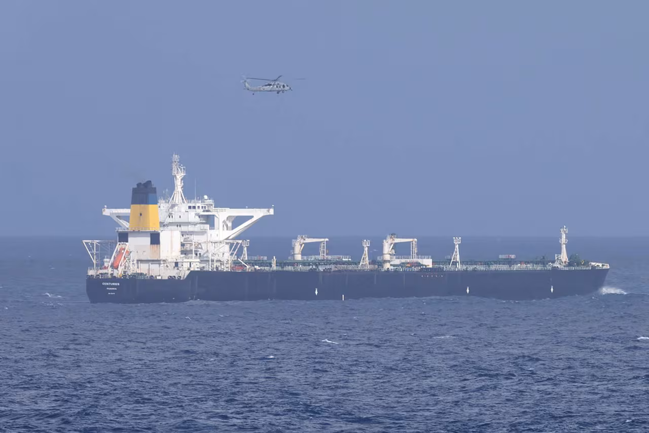 an aircraft hovers above a larges vessel in the sea