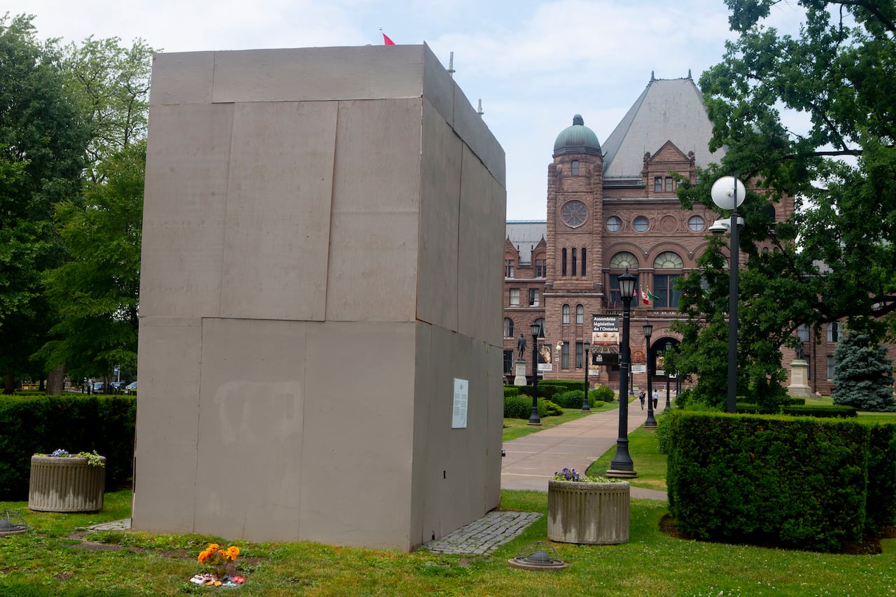 Children's shoes lie at the foot of a boxed-up statue of Sir John A. MacDonald, which stands on the grounds of the Ontario legislature at Queen's Park, in Toronto.