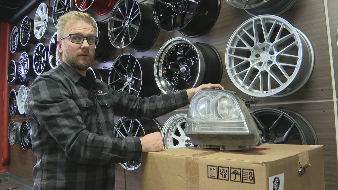 A man holds up a car headlight.