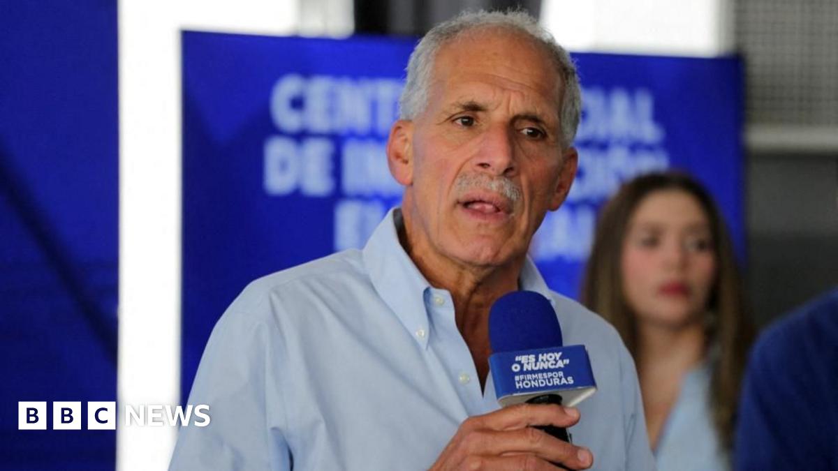 Christmas decorations light up a busy street in central London. There is a double-decker bus and pedestrians on the street.