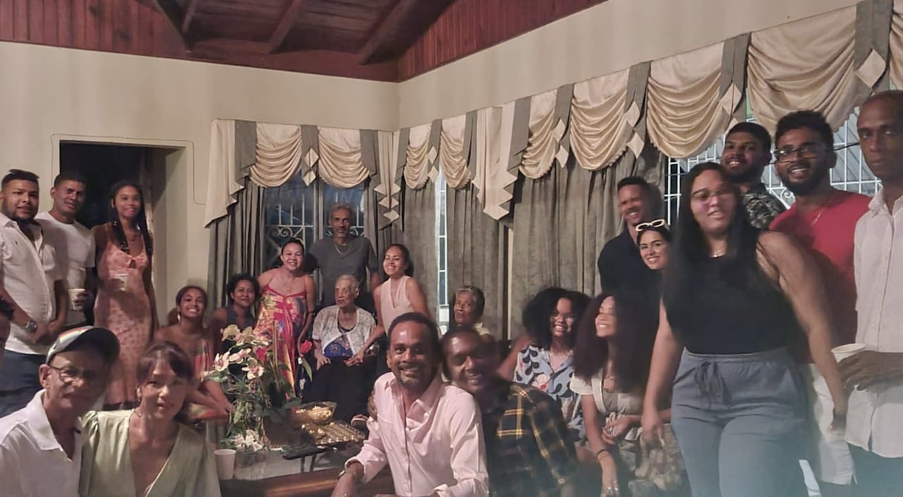 More than 20 people gather in a living room for a family photo.