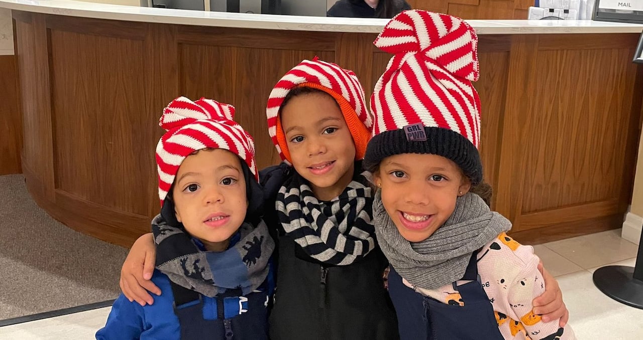 Three children in white and red striped hats and snowpants.
