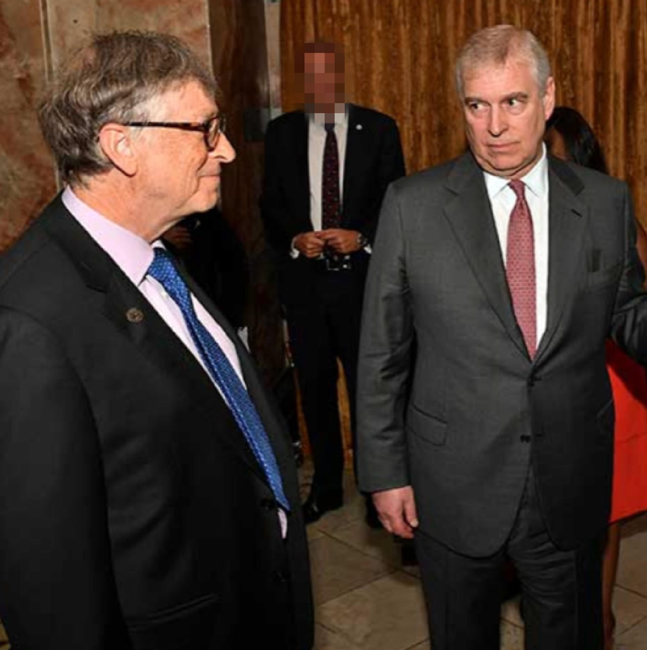 Two men dressed in suits standing next to one another.