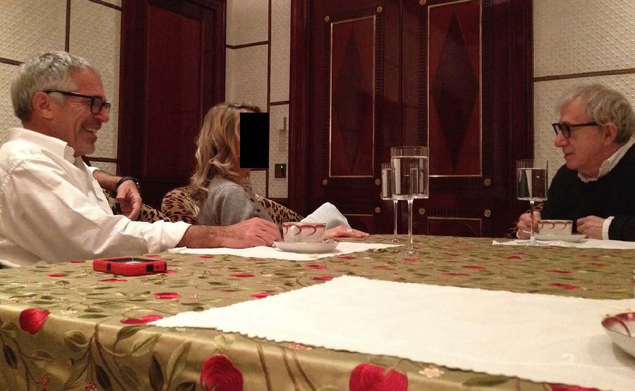 Jeffrey Epstein and Woody Allen face each other across at a table, with an unidentified woman whose face is obscured sitting between them.