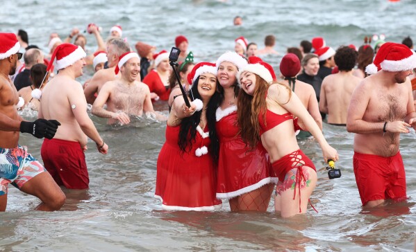 People take to the sea at Helen's Bay, Northern Ireland, for the annual Christmas Eve swim in the cold waters in Belfast Lough to raise money for Dementia NI & Air Ambulance NI, Wednesday, Dec. 24, 2025. (AP Photo/Peter Morrison)
