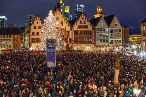 People gather at Roemerberg square to attend the city's bell ringing on Christmas Eve in Frankfurt, Germany, Wednesday, Dec. 24, 2025. (AP Photo/Michael Probst)