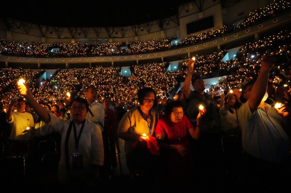 People hold electric candles as they sing during a Christmas Eve service at Indonesia Arena stadium in Jakarta, Indonesia, Wednesday, Dec. 24, 2025. (AP Photo/Tatan Syuflana)