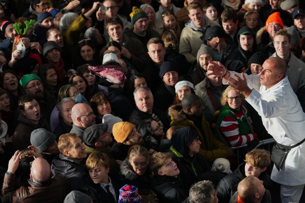 A piece of meat is thrown to the buyer in the crowd during the annual Christmas Eve meat auction at Smithfield Market in London, Wednesday, Dec. 24, 2025. (AP Photo/Kirsty Wigglesworth)
