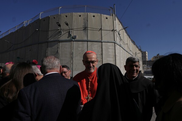 Latin Patriarch Pierbattista Pizzaballa, the top Catholic clergyman in the Holy Land, is received by local community while crossing an Israeli military checkpoint from Jerusalem ahead of celebrations at the Church of the Nativity, traditionally believed to be the birthplace of Jesus, on Christmas Eve, in the West Bank city of Bethlehem, Wednesday, Dec. 24, 2025. (AP Photo/Mahmoud Illean)