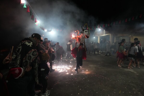 A child runs with a traditional vaca loca, or crazy cow, during Christmas celebrations in Quingeo, Ecuador, Tuesday, Dec. 23, 2025. (AP Photo/Dolores Ochoa)