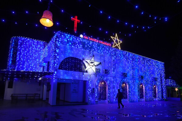 A man walks past an illuminated church on the eve of Christmas in Ahmedabad, India, Wednesday, Dec. 24, 2025. (AP Photo/Ajit Solanki)