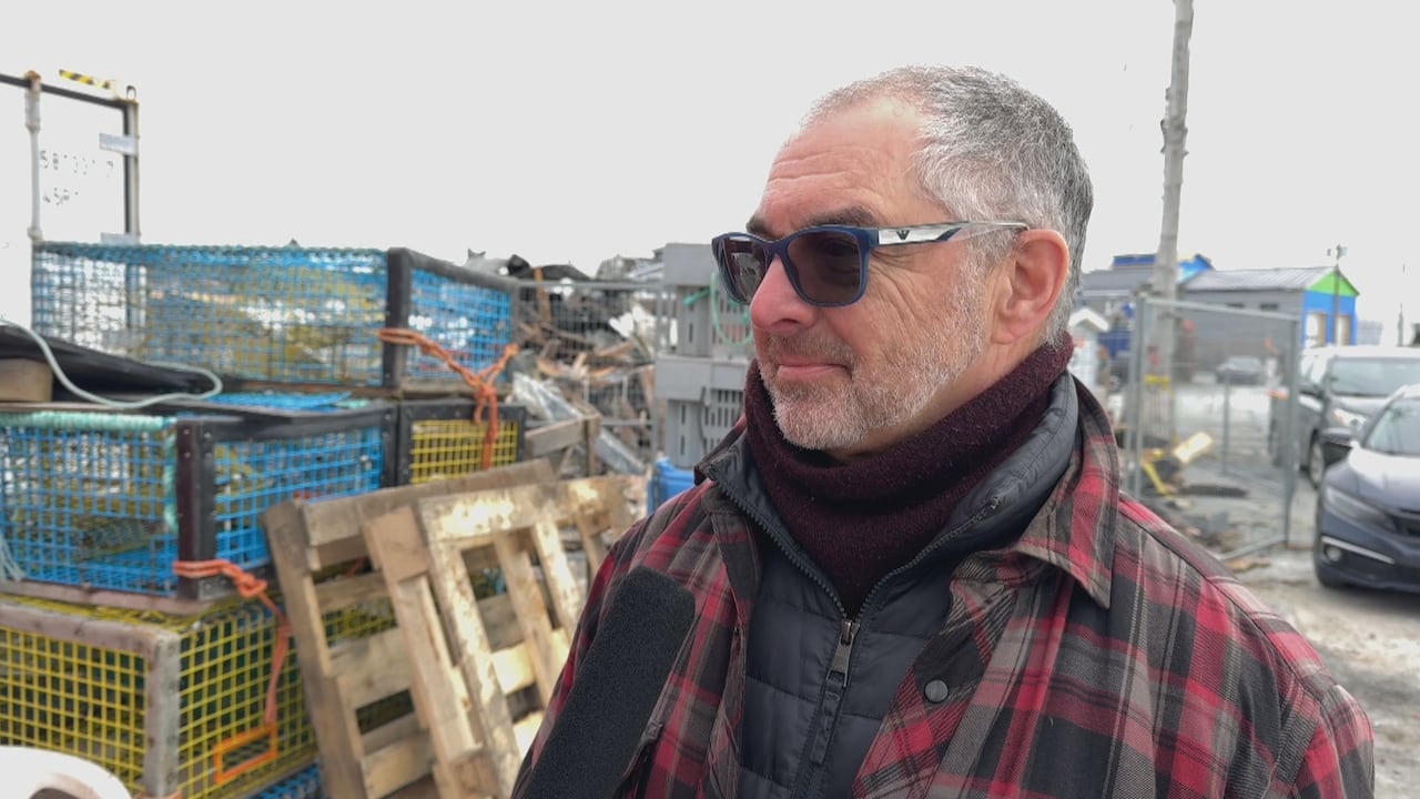 A man wearing sunglasses stands in front of some lobster crates.
