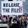 A protester with his back to the camera outside the U.S. Capitol holds a sign that says "release all the files!" 